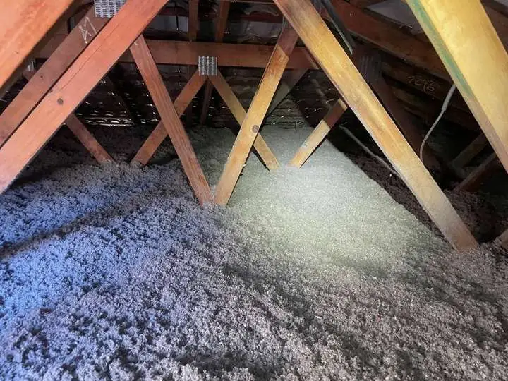 Thick grey cellulose fibre insulation packed evenly between roof trusses under a tiled roof — Lawnton