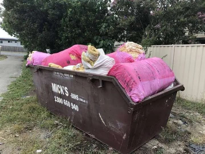 A skip bin filled with old pink and yellow fibreglass batts removed during an insulation removal job — Strathpine, 2016
